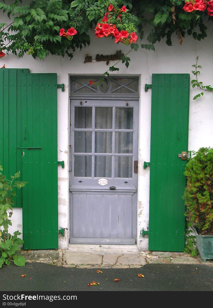 Grey wooden door with green shutters