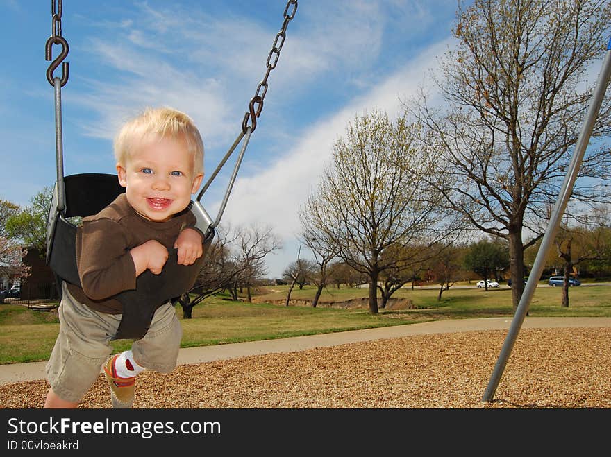 Boy smiling on swing set. Boy smiling on swing set.