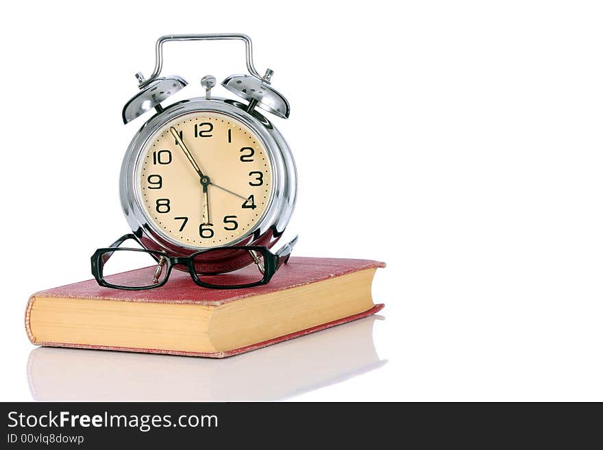 Book with alarm clock and eyeglasses on white background