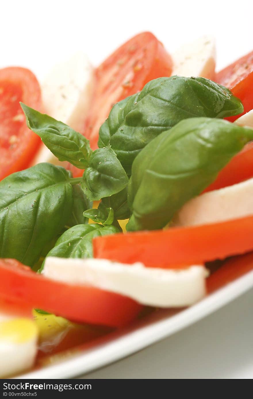 Closeup of tricolore salad, mozarella with sweet tomatoes and basil with a drizzling of olive oil. Closeup of tricolore salad, mozarella with sweet tomatoes and basil with a drizzling of olive oil.