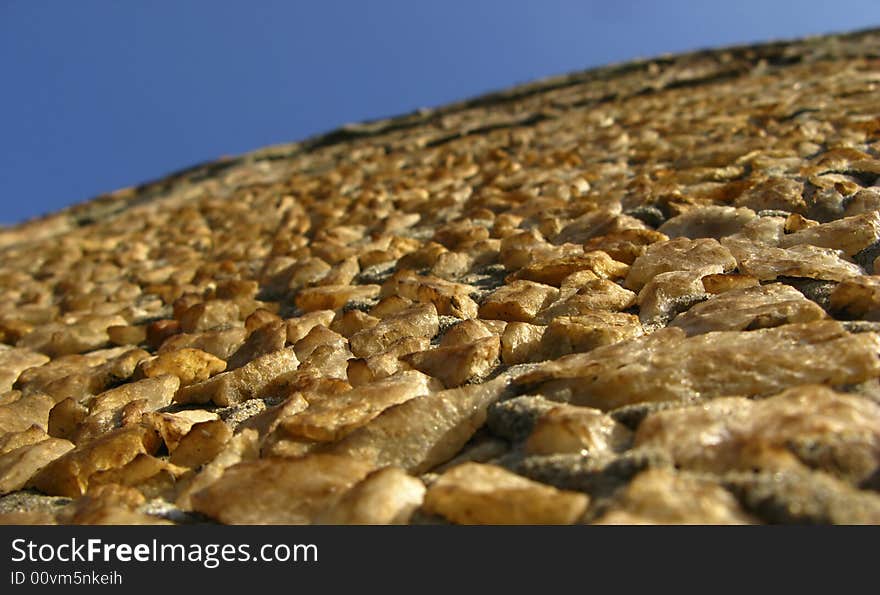 Fragment of wall, surface laid out from stones on blue sky background