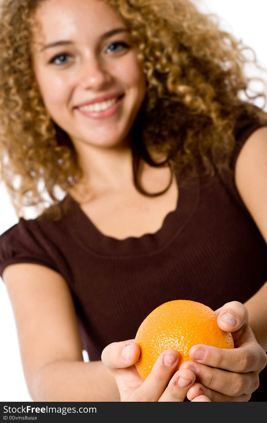 A pretty smiling young woman holding an orange (focus on orange). A pretty smiling young woman holding an orange (focus on orange)