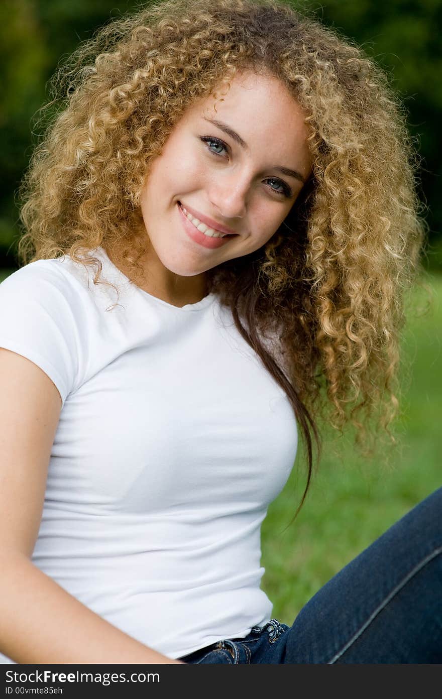 A young attractive woman sitting outside in the park. A young attractive woman sitting outside in the park