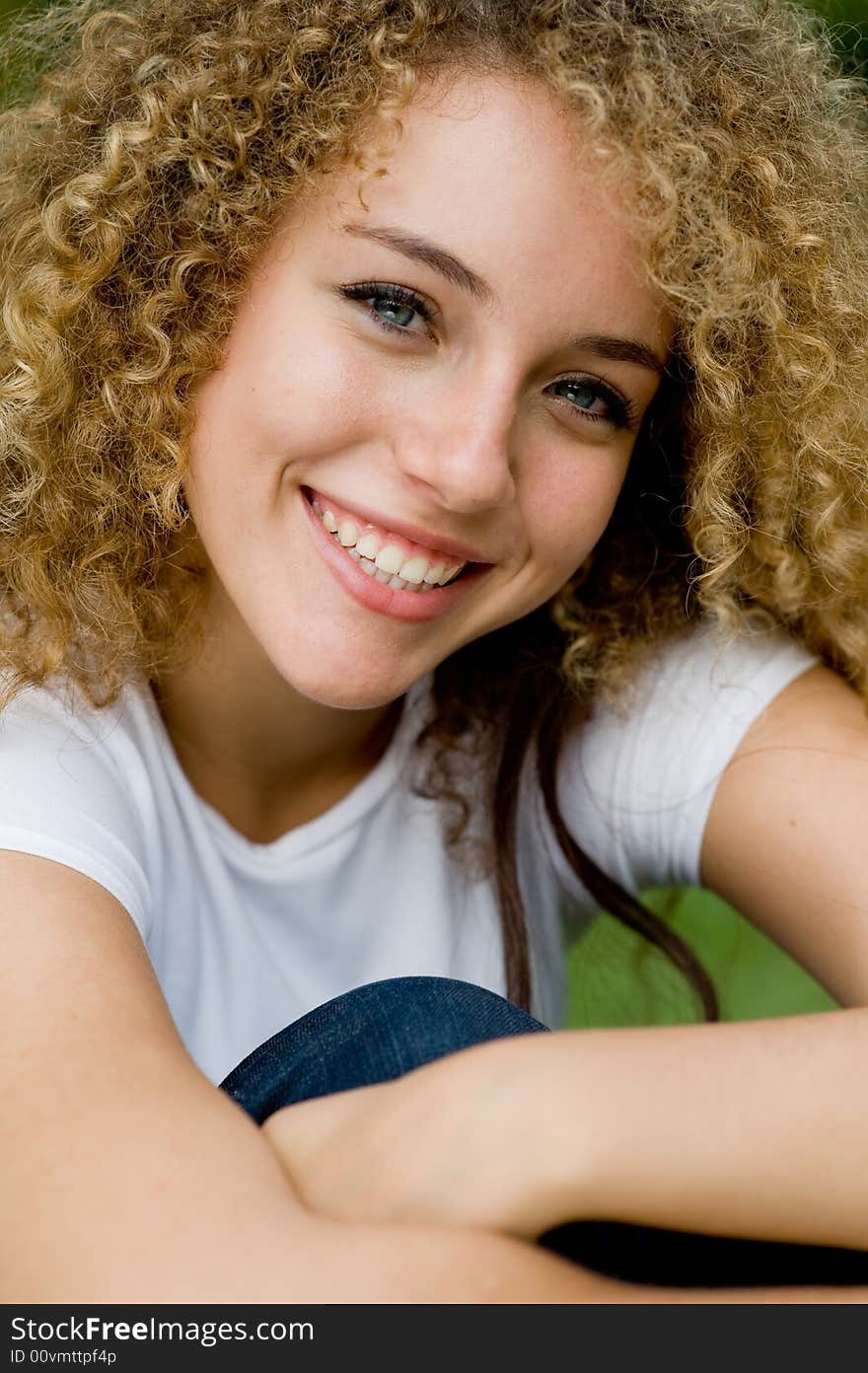 A young attractive woman sitting outside in the park. A young attractive woman sitting outside in the park