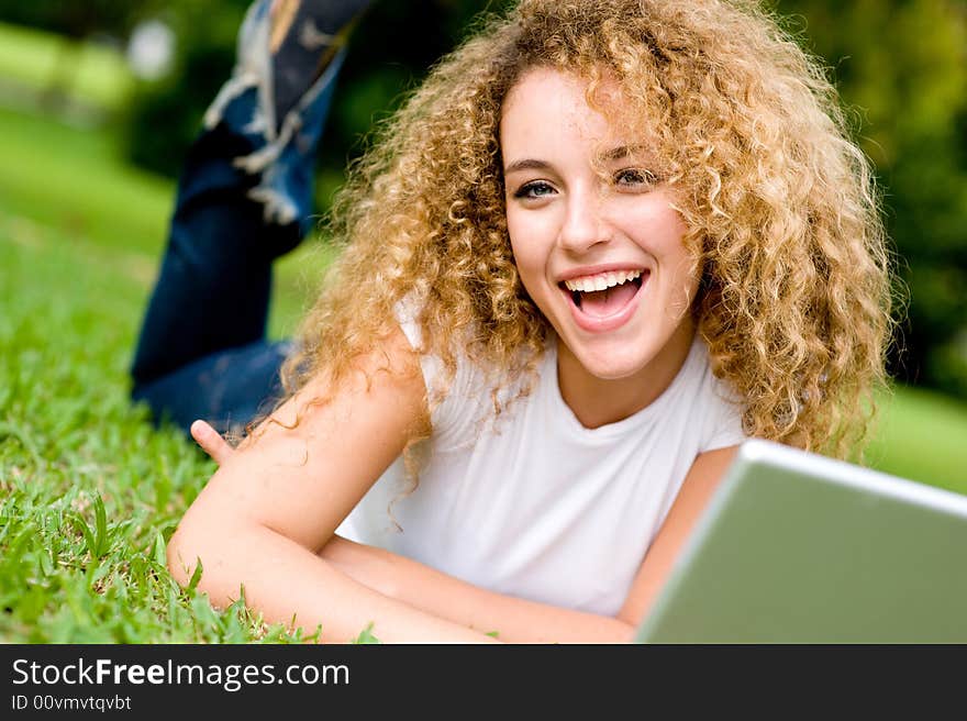 A young woman lying on the grass with laptop computer. A young woman lying on the grass with laptop computer