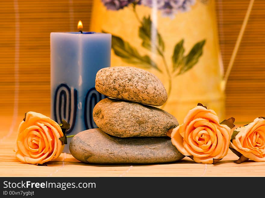 Still life with three round stone and rose and candle