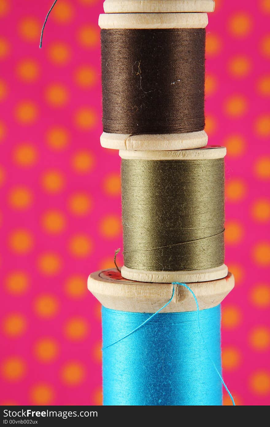 Spools of thread stacked in front of a bright polka dot background. Spools of thread stacked in front of a bright polka dot background