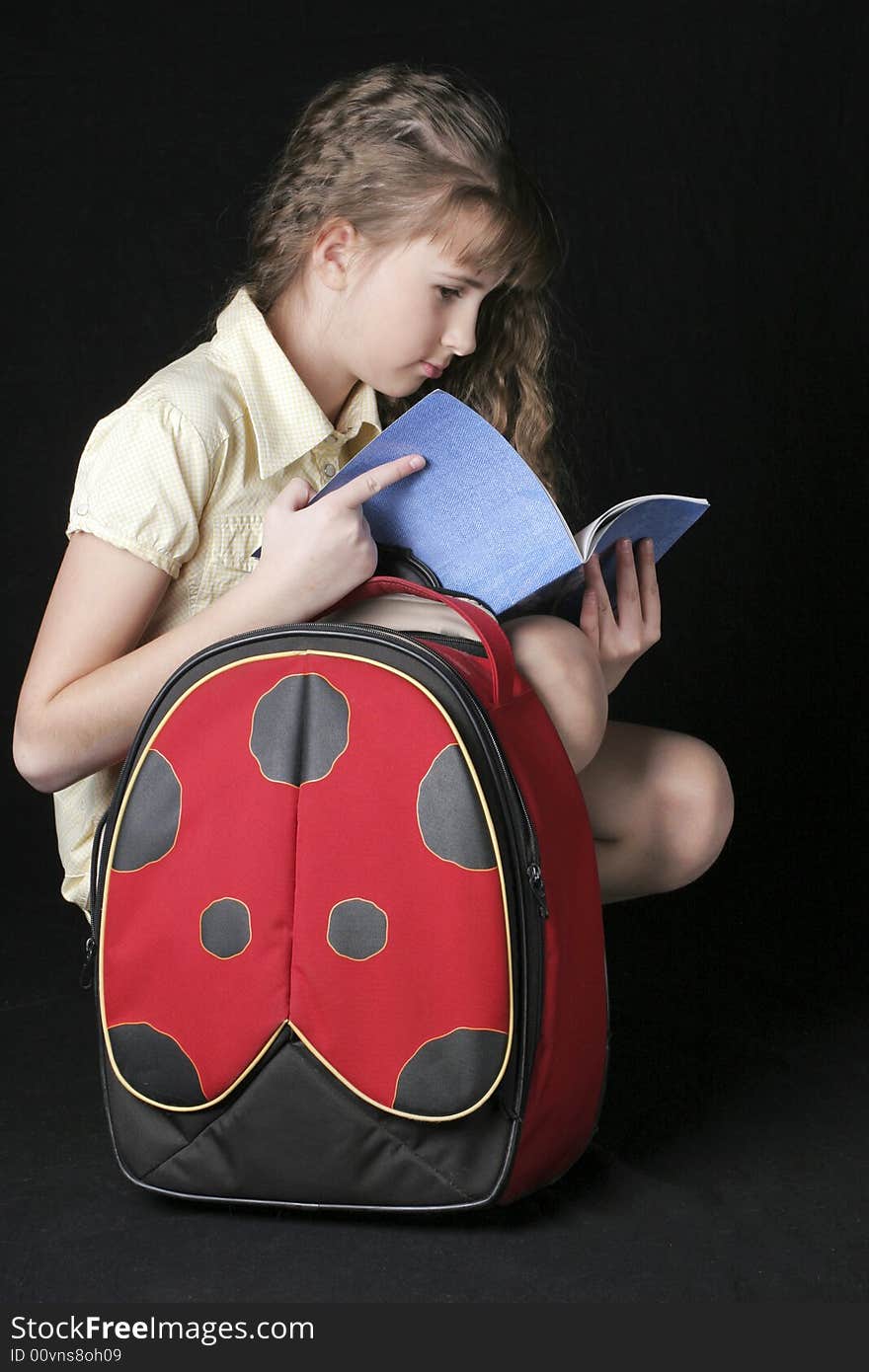 Girl with bag, looking to notebook on black background