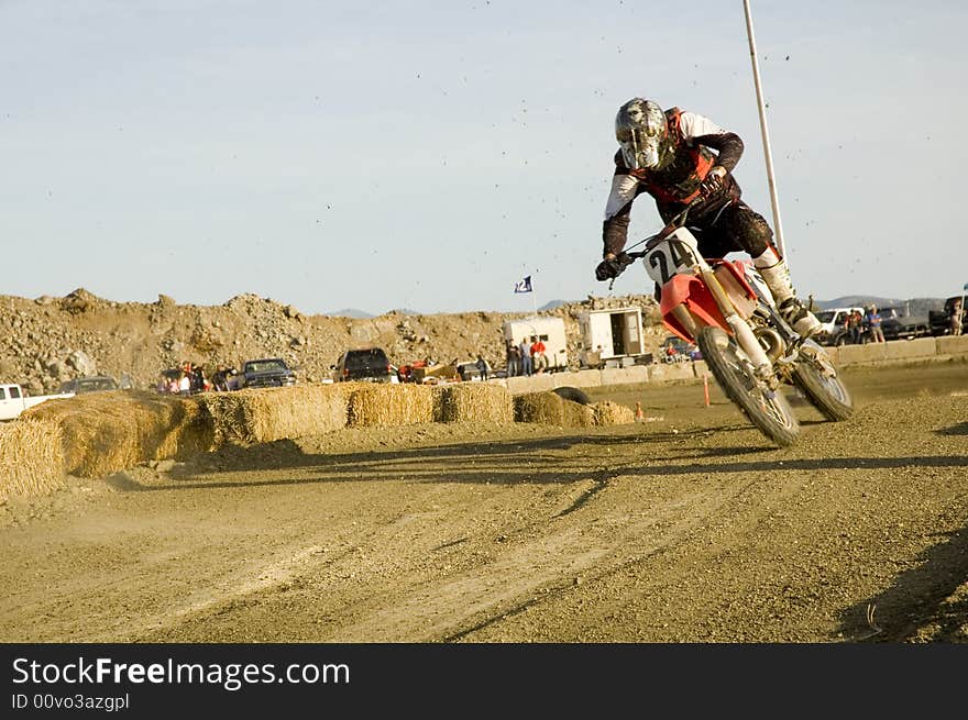 Dirt bike racer leaning into the curve and in the air