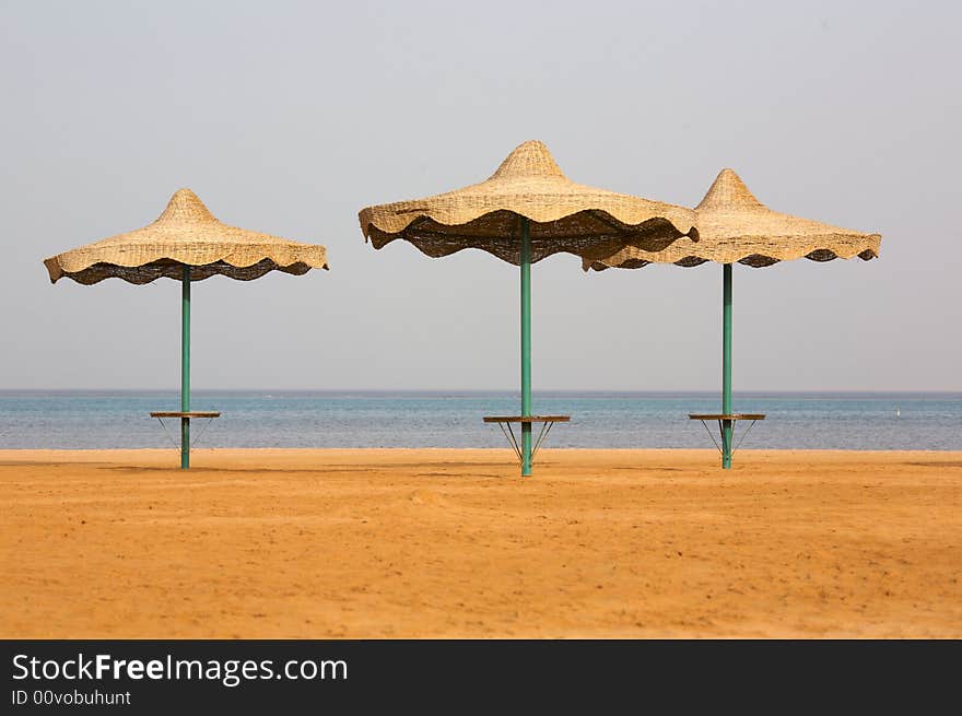 Beach on the coast of the Red Sea. Three single beach umbrella. Morning. (12,8 MP FullFrame). Beach on the coast of the Red Sea. Three single beach umbrella. Morning. (12,8 MP FullFrame)