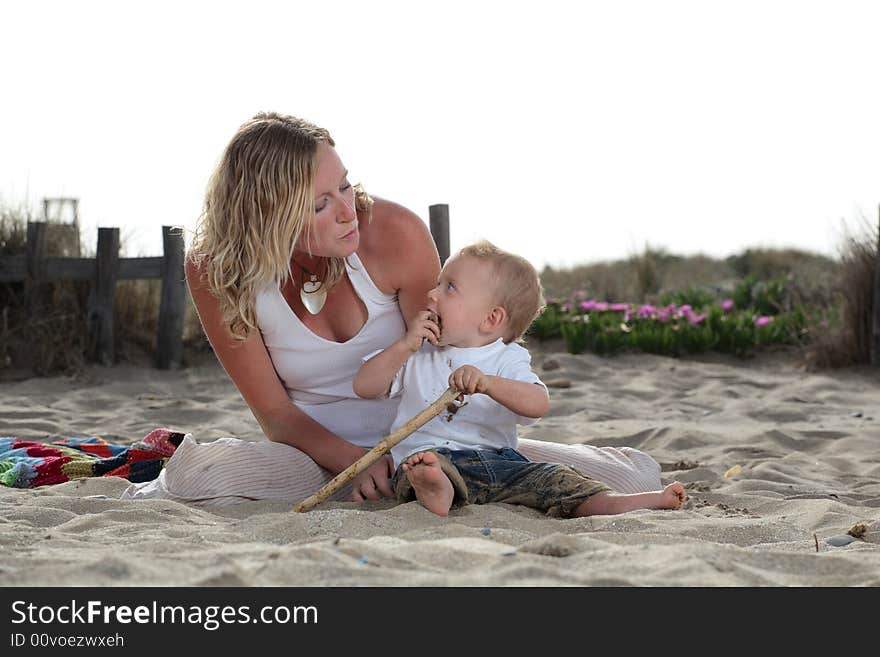 Young mommy blowing kisses at her son while playing on the beach