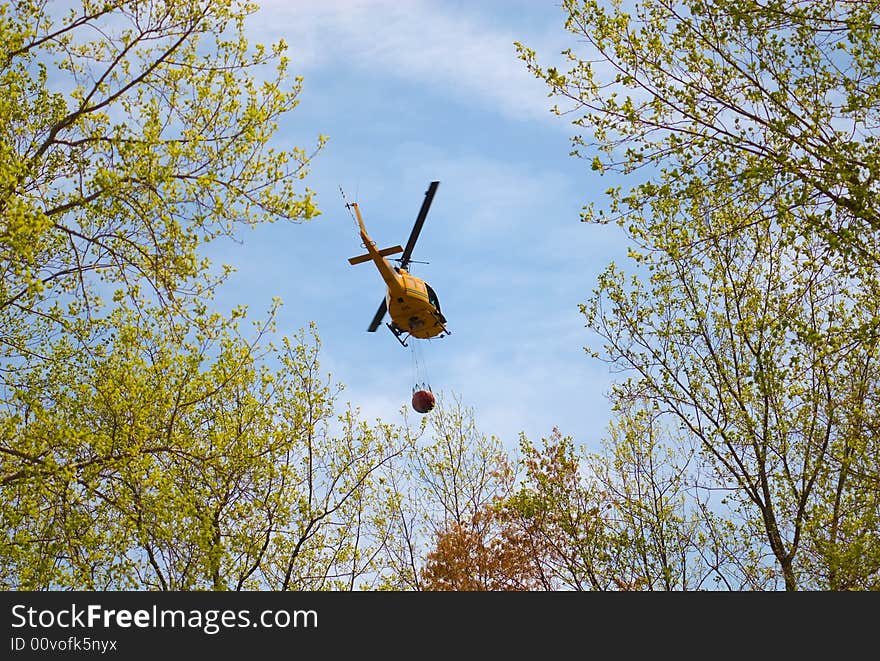 A rescue helicopter carrying water to a forest fire.