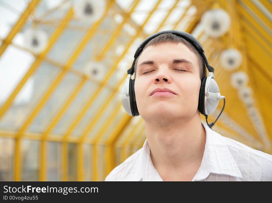 Young man listens music on footbridge