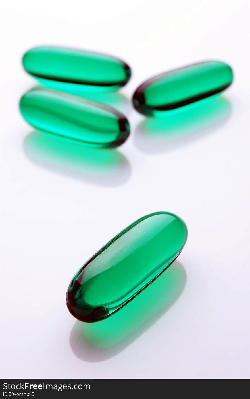 Green capsules on white background, vertical image