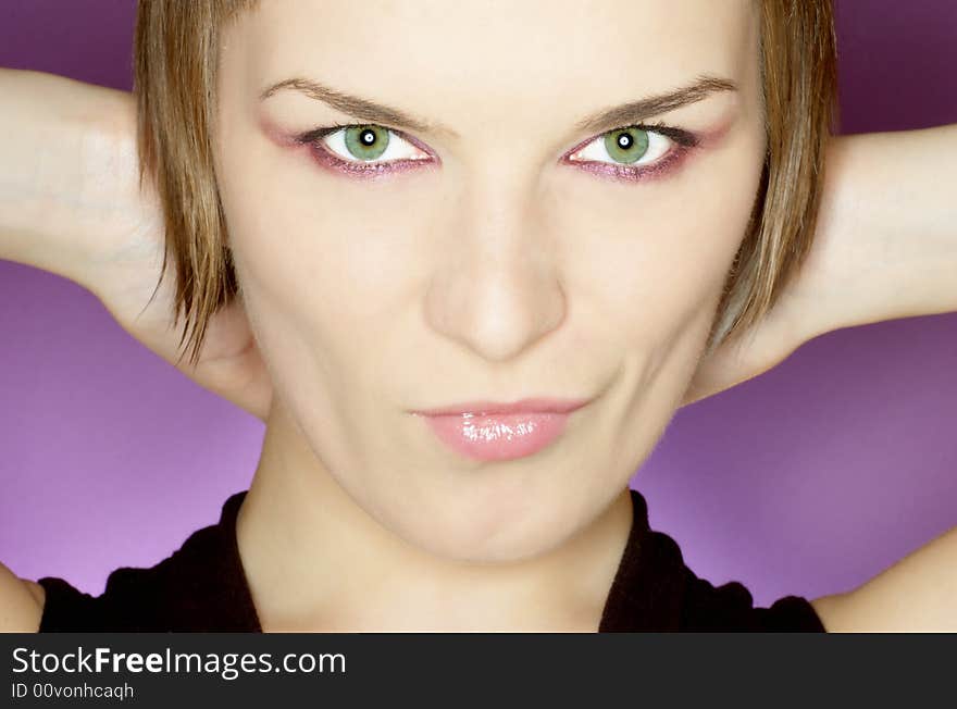 Beautiful woman with green eyes on purple background, hands on her neck, close up