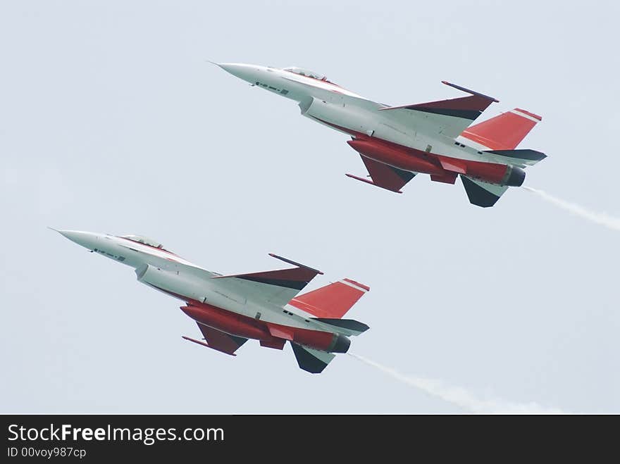 Two white and red F-16 fighter airplanes flying in formation. Two white and red F-16 fighter airplanes flying in formation