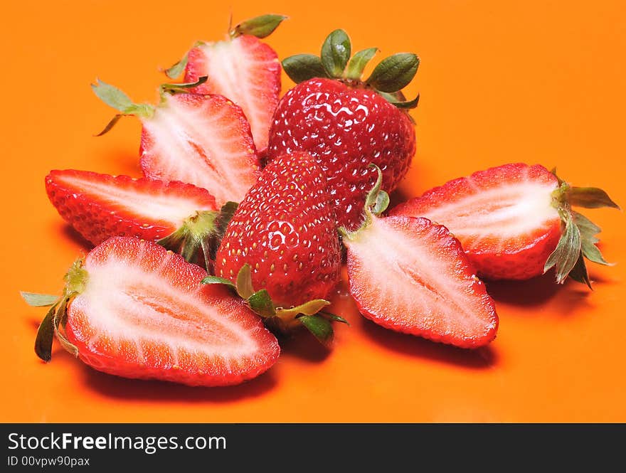 Close up of a group of fresh, succulent strawberries in orange background