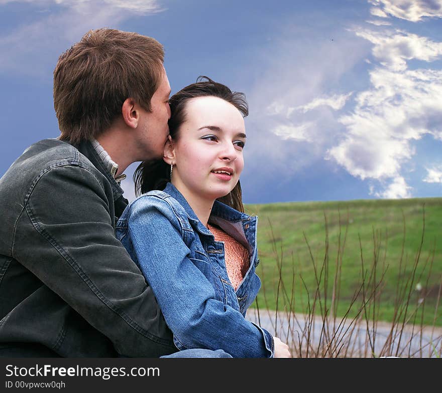 Guy and girl sits on a grass on a background of the sky. Guy and girl sits on a grass on a background of the sky