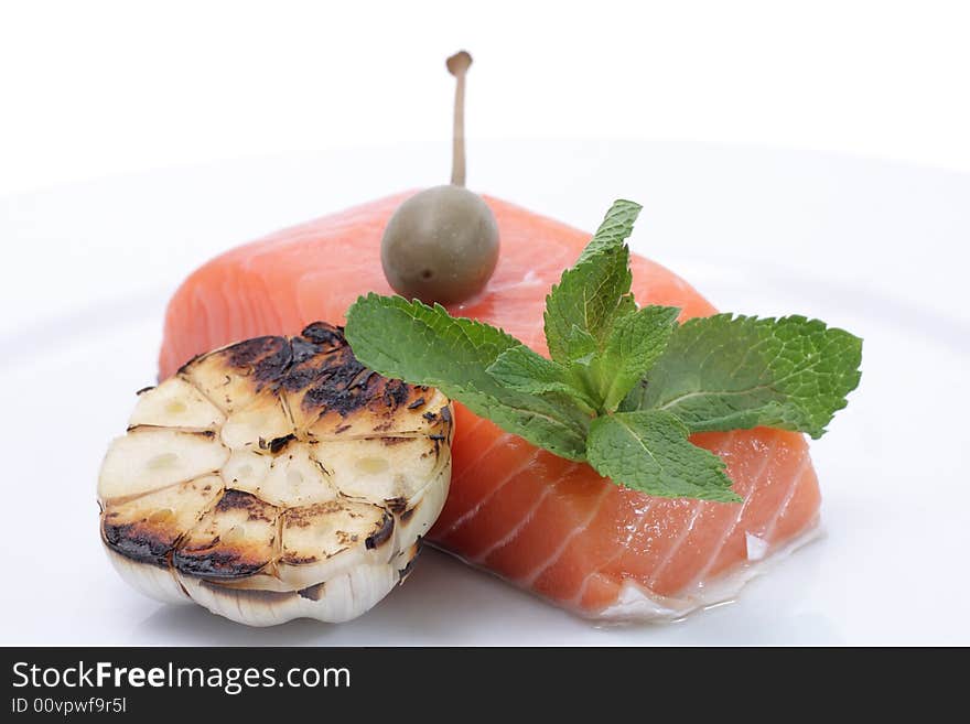 Fresh salmon, garlic and green on a plate. Isolated on a white background. Fresh salmon, garlic and green on a plate. Isolated on a white background