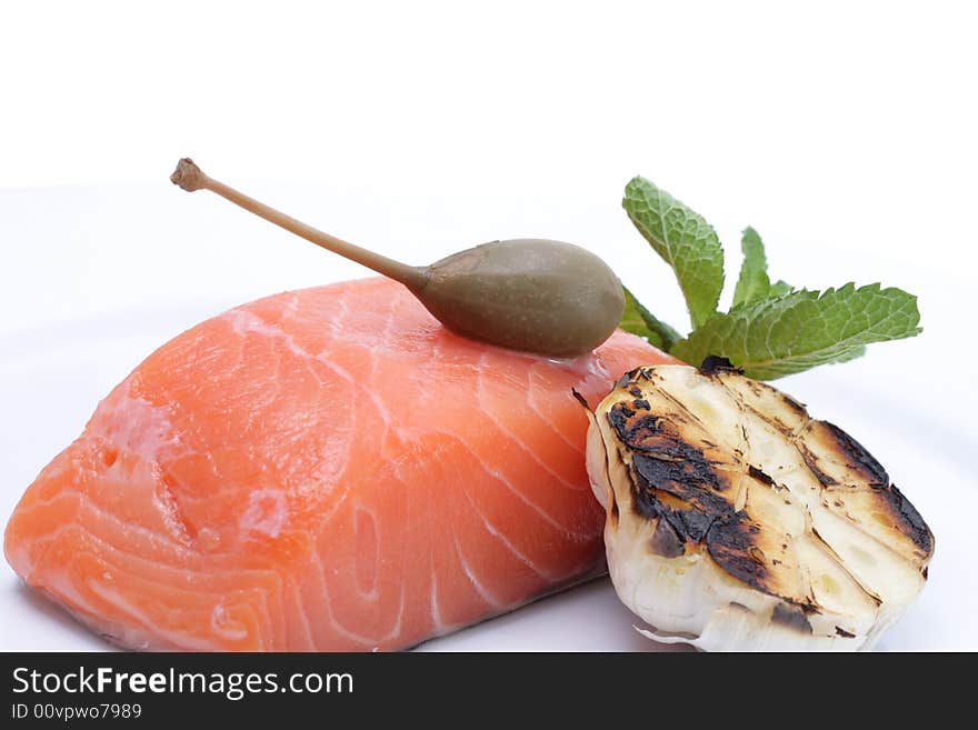 Fresh salmon, garlic and green on a plate. Isolated on a white background. Fresh salmon, garlic and green on a plate. Isolated on a white background