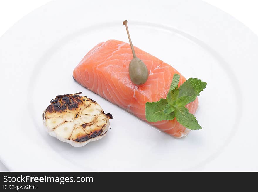 Fresh salmon, garlic and green on a plate. Isolated on a white background. Fresh salmon, garlic and green on a plate. Isolated on a white background