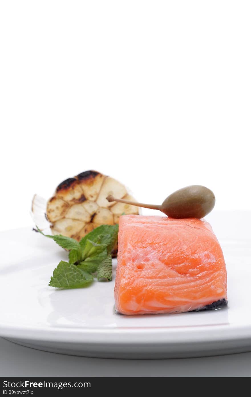 Fresh salmon, garlic and green on a plate. Isolated on a white background. Fresh salmon, garlic and green on a plate. Isolated on a white background