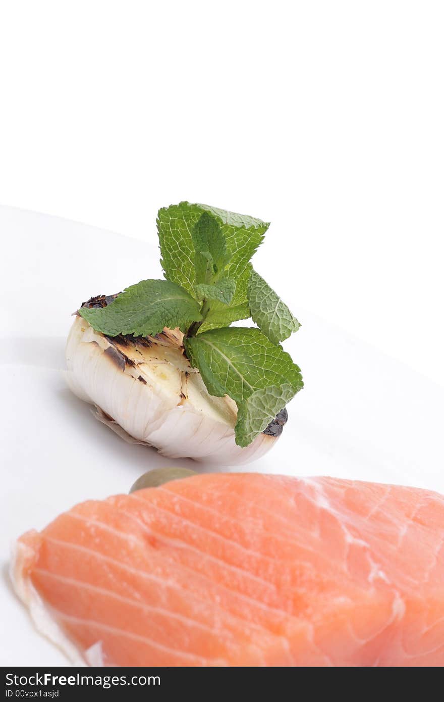 Fresh salmon, garlic and green on a plate. Isolated on a white background. Fresh salmon, garlic and green on a plate. Isolated on a white background