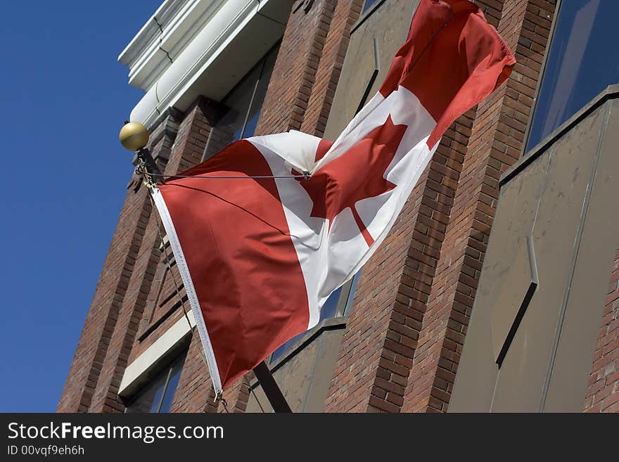 Canadian flag in front of administrative building with blue sky