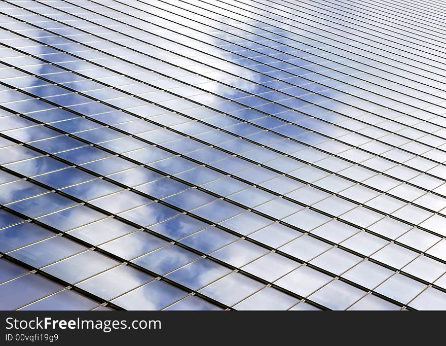 Beautiful modern skyscraper with glass panels reflecting moody sky.  Great for business backgrounds. Beautiful modern skyscraper with glass panels reflecting moody sky.  Great for business backgrounds