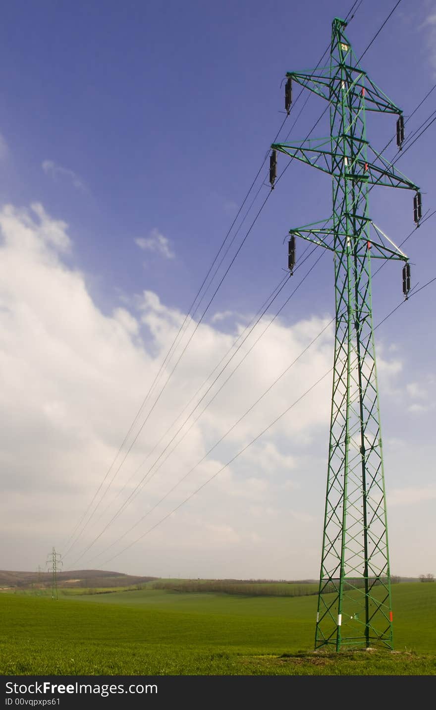 Many electricity pylons with wire in the green fields