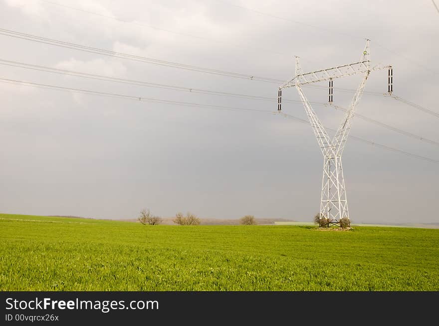 Many electricity pylons with wire in the green fields. Many electricity pylons with wire in the green fields