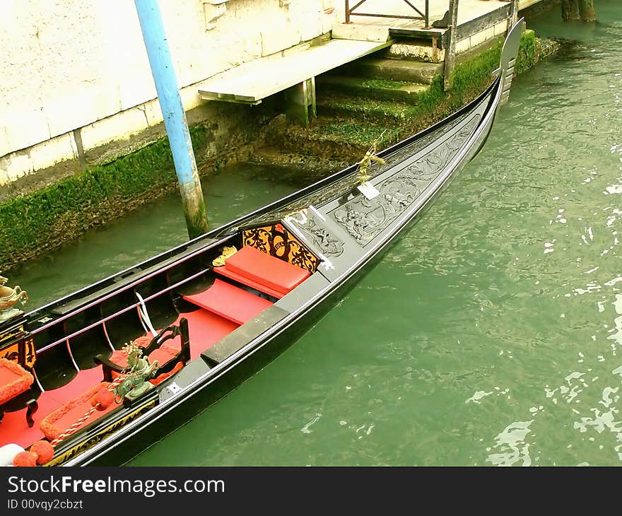 Italy, Venice postcard: Venetian gondola in a back canal, embankment and green canal waters