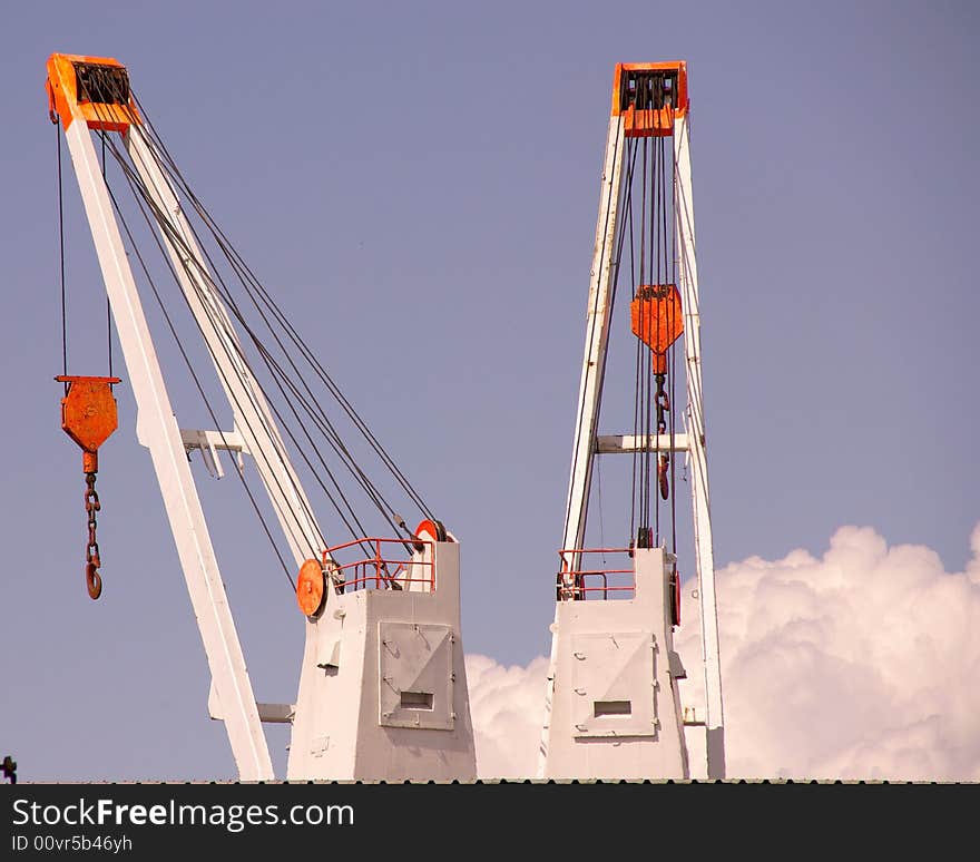 Two cranes in a trans-shipment harbour and a blue sky with one cloud