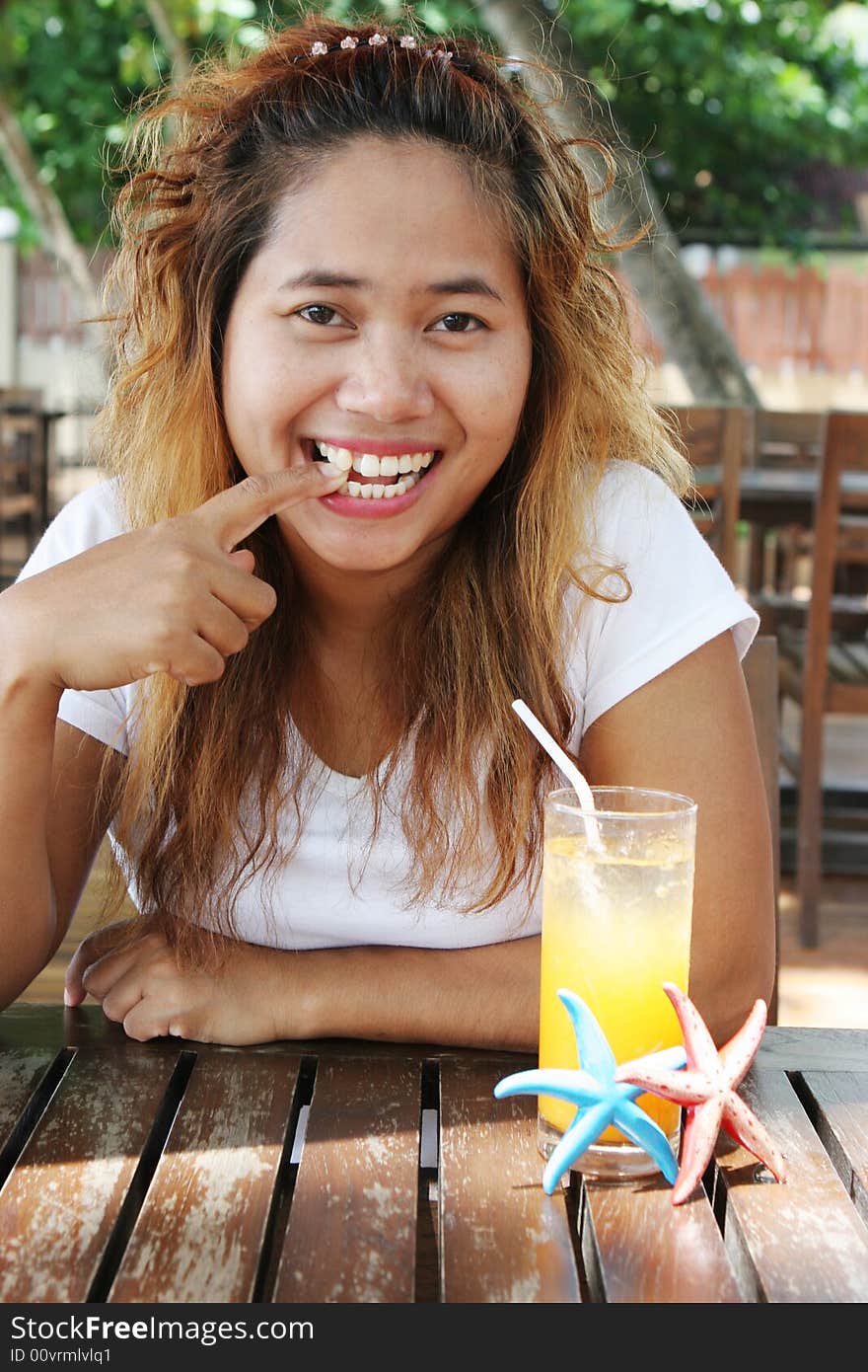 Asian girl having a glass of orange juice at an outdoor cafe. Asian girl having a glass of orange juice at an outdoor cafe.