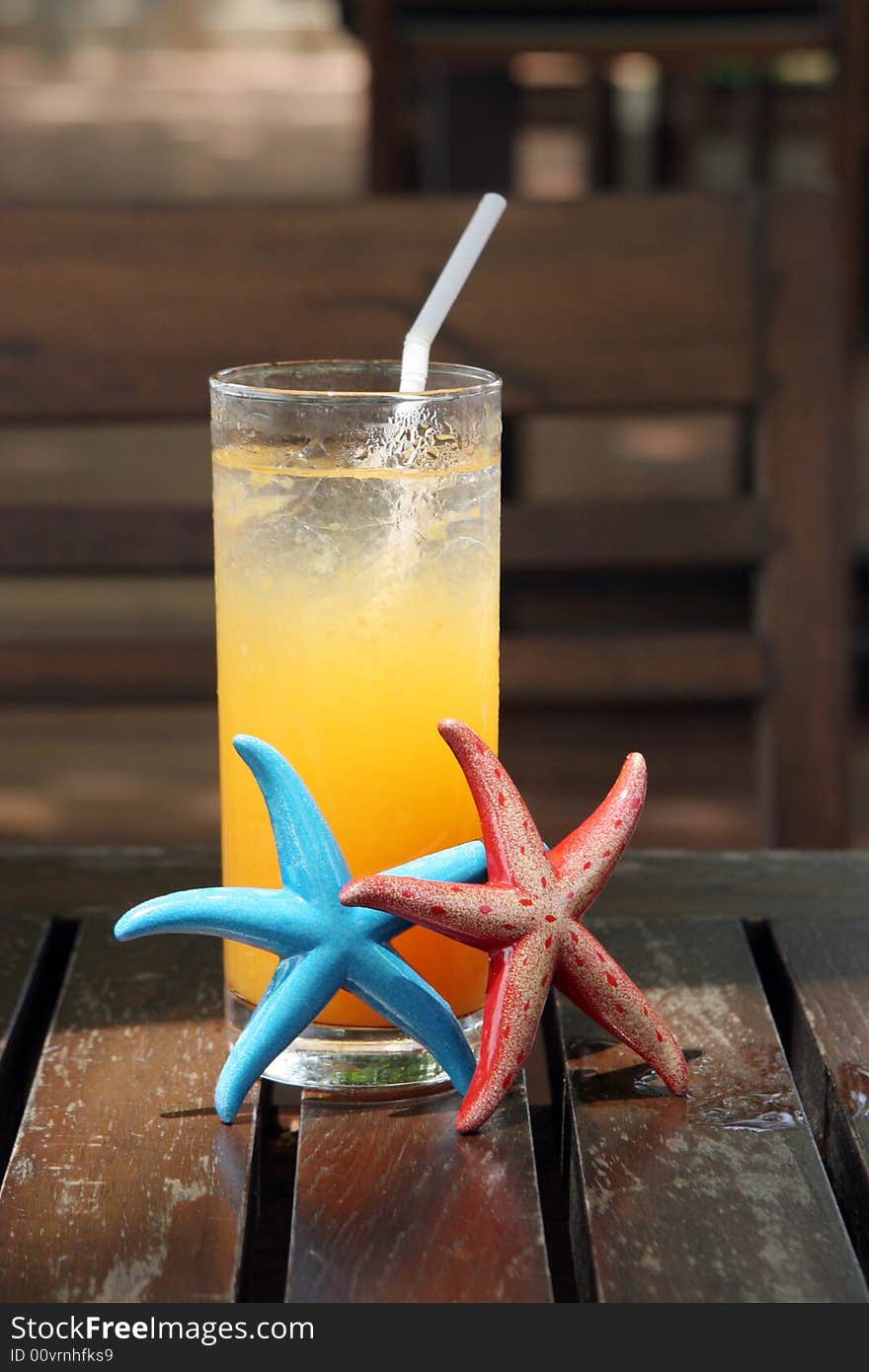 Glass of orange juice with starfish next to it.