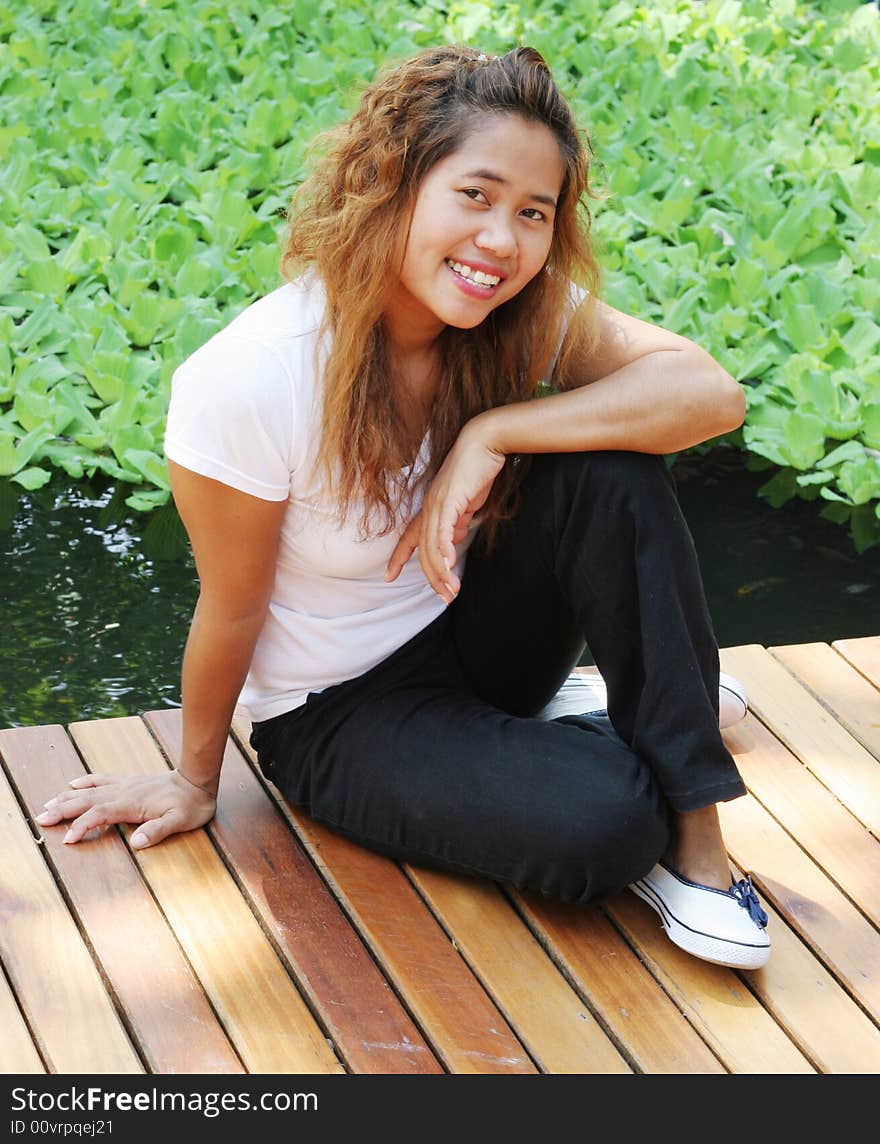 Portrait of a happy Asian woman sitting on a deck. Portrait of a happy Asian woman sitting on a deck.