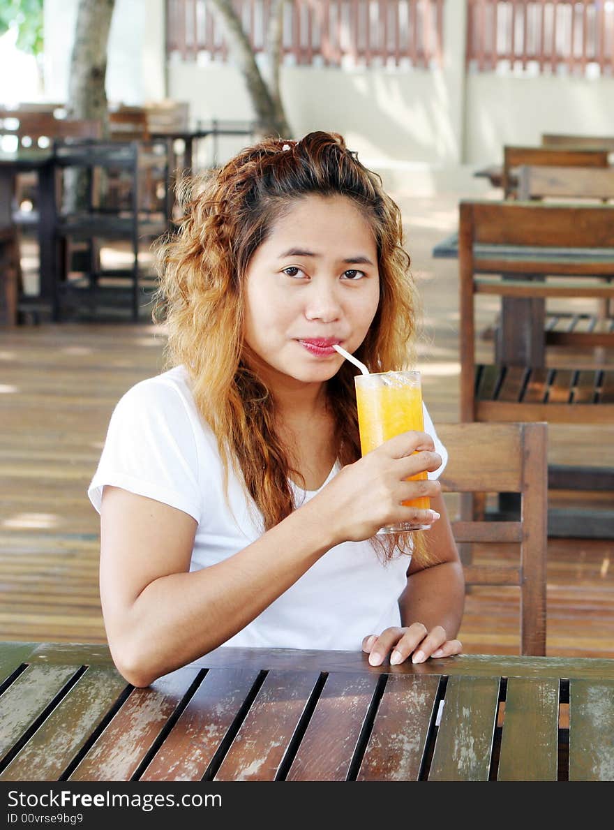 Pretty Asian girl having a drink at a cafe. Pretty Asian girl having a drink at a cafe.