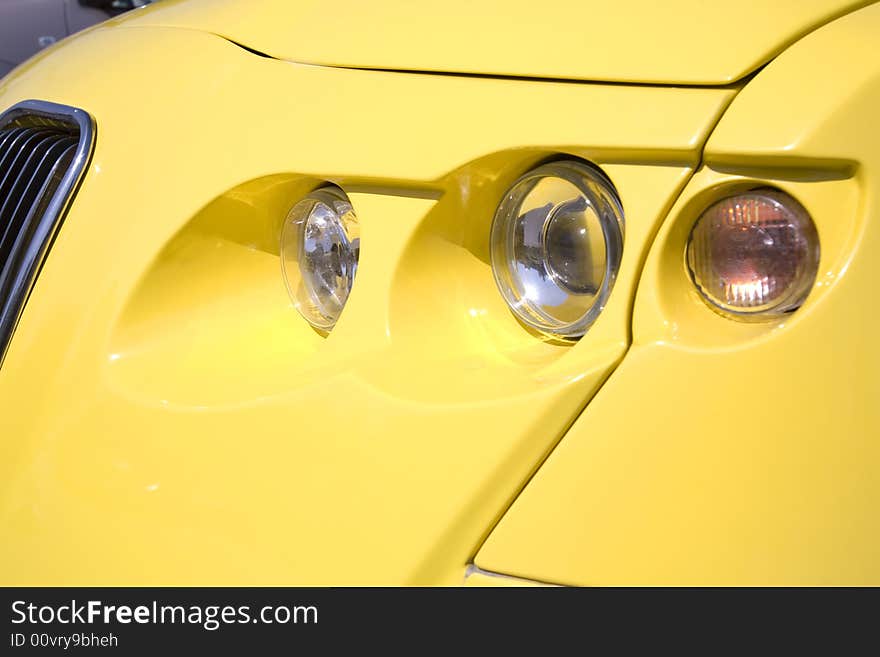 Close-up of a headlight on yellow modern car. Close-up of a headlight on yellow modern car