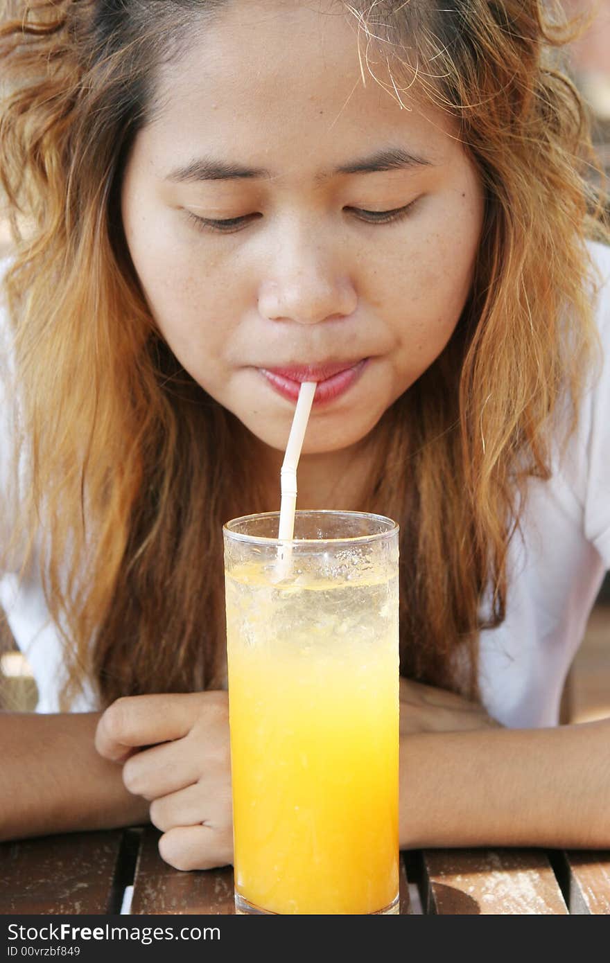 Close-up portrait of a pretty Thai woman drinking juice.