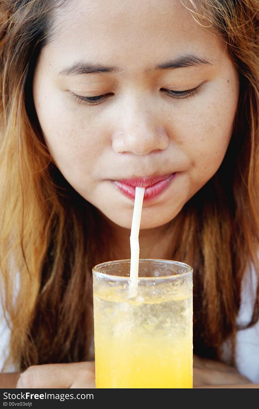 Close-up portrait of a pretty Thai woman drinking juice.