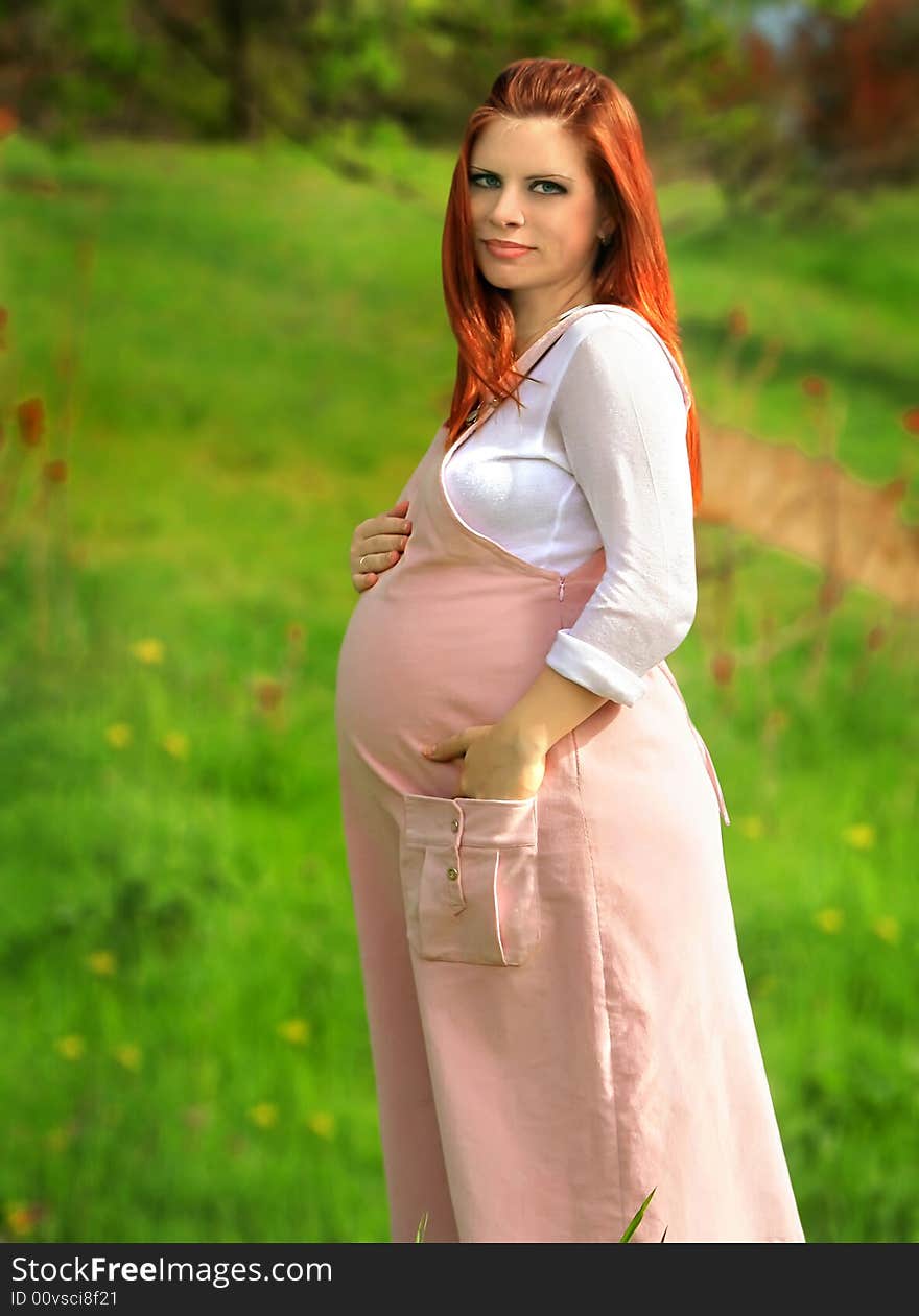 Beautiful and young pregnant girl walks on spring park: a good illustration for magazine about pregnant women and for women