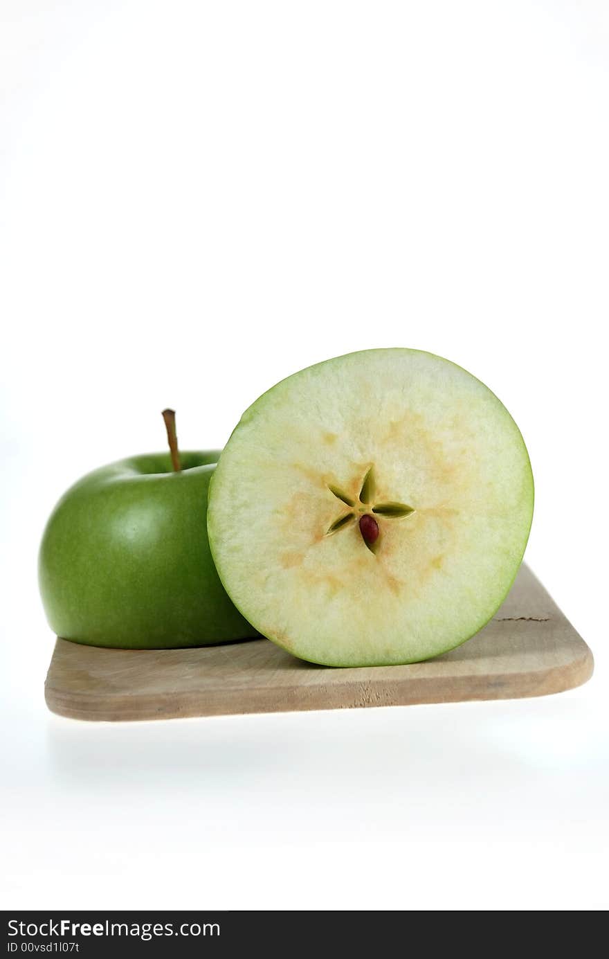 A fresh cut green apple placed on wooden cutting board. A fresh cut green apple placed on wooden cutting board