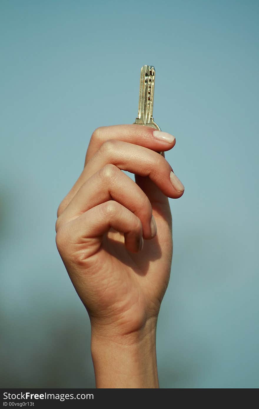 Key between the fingers with the sky in the background. Key between the fingers with the sky in the background