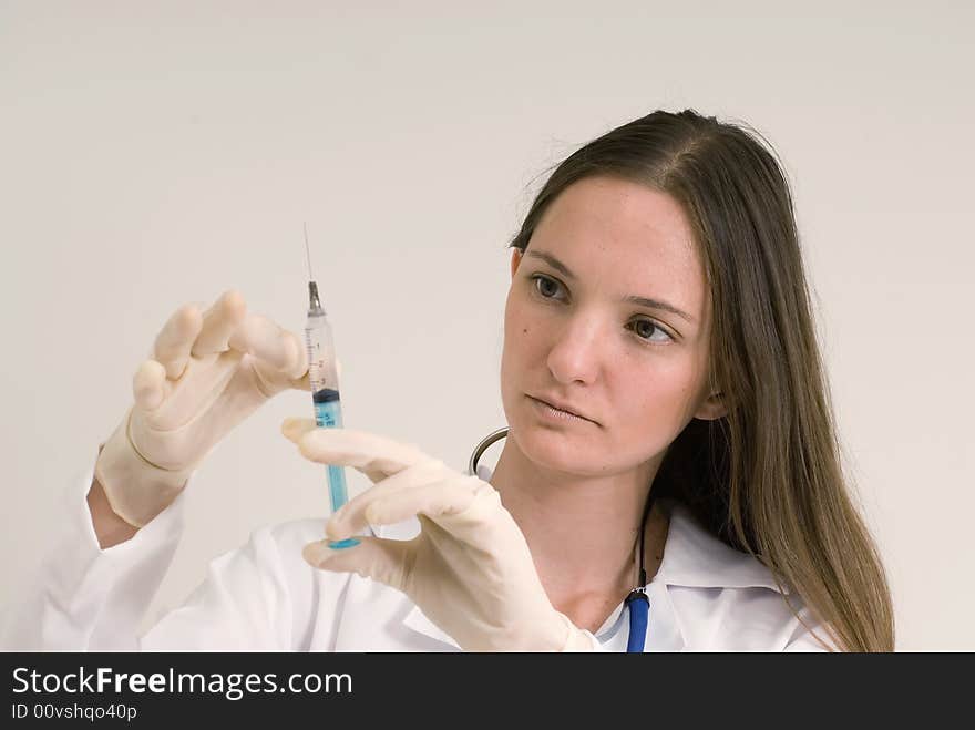 Young female doctor with gloved hands tapping a syringe. Isolated. Young female doctor with gloved hands tapping a syringe. Isolated.