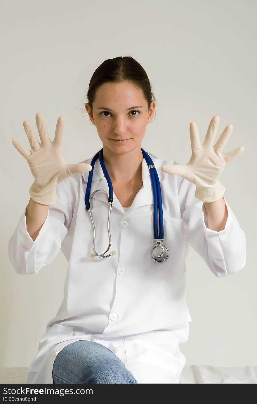 Young female doctor holding out her gloved hands. Isolated. Young female doctor holding out her gloved hands. Isolated.