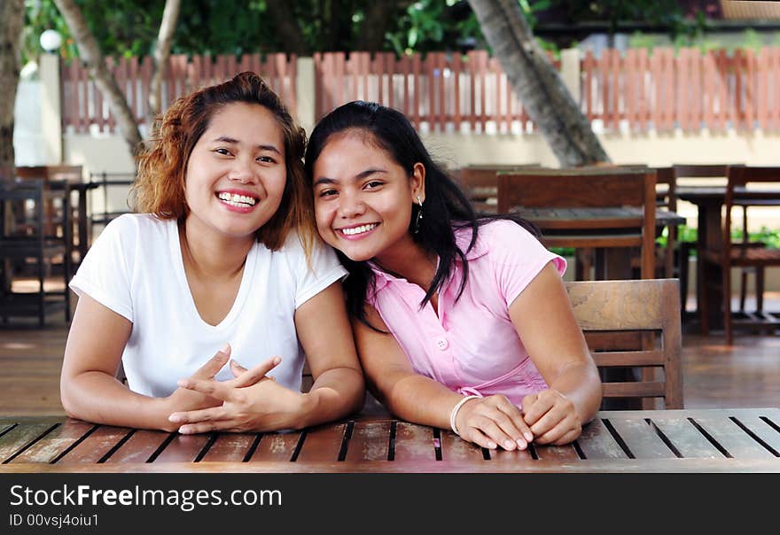 Pretty Asian girls sitting at a table outside. Pretty Asian girls sitting at a table outside.