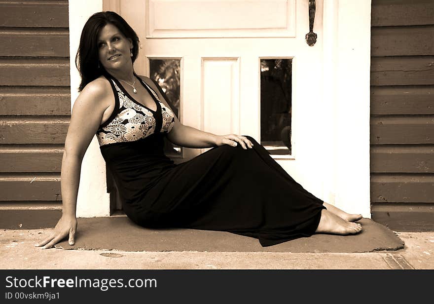 Black and white of a woman sitting in the doorway with tropical island type architecture. Black and white of a woman sitting in the doorway with tropical island type architecture