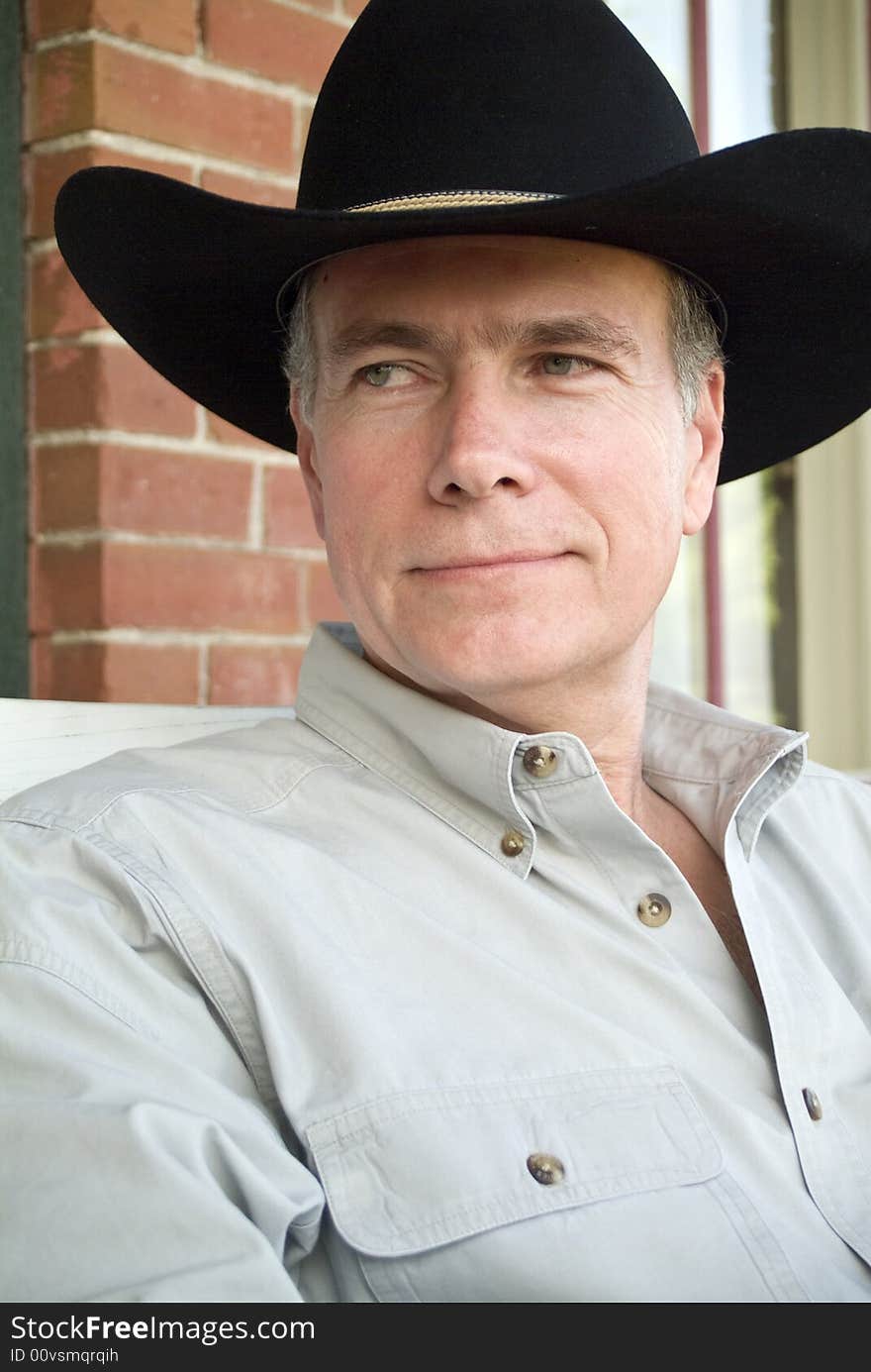 A closeup of a man in a cowboy hat relaxing on a porch. A closeup of a man in a cowboy hat relaxing on a porch.