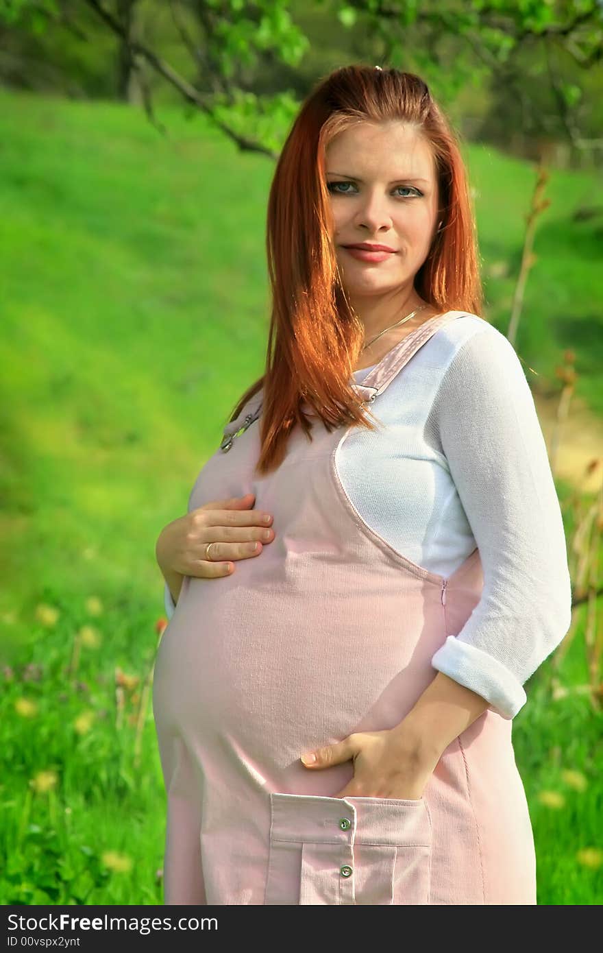 Beautiful and young pregnant girl walks on spring park: a good illustration for magazine about pregnant women and for women