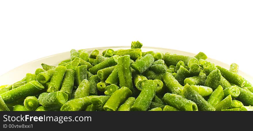 Frozen string beans in plate close-up over white